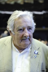 retrato de José "Pepe" Mujica Cordano: tiene el pelo blanco y bigote gris; lleva una chaqueta a cuadros y una camisa blanca, sin corbata.
