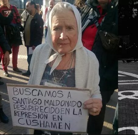 una señora vieja con pañuelo blanco en la cabeza sostiene una pequeña pancarta que dice "Buscamos a Santiago Maldonado, desaparecido en la represión en Cushamen"